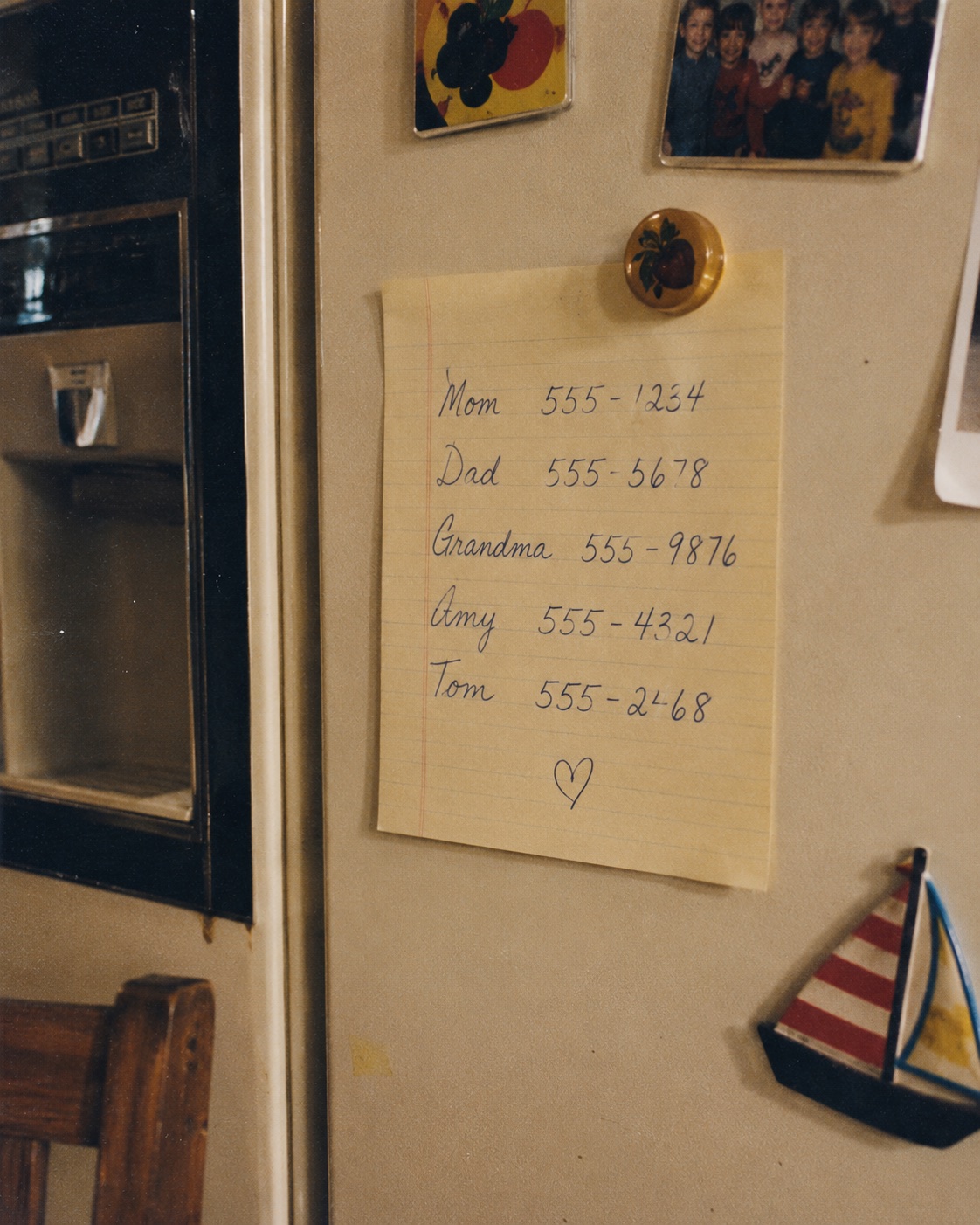 Handwritten family phone numbers on a refrigerator